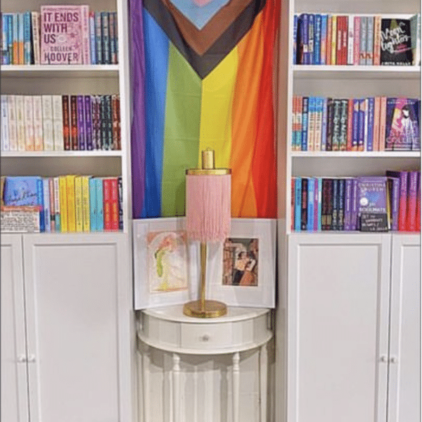 A Pride Flag surrounded by bookshelves.